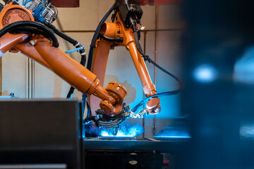 Orange color robotic arms manufacturing in industrial factory