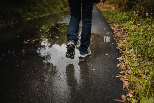 Legs of woman walking on wet footpath during rainy season