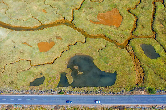 Spain, Andalusia, Aerial view of highway cutting through green marsh in Marismas del Odiel nature reserve