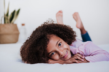 Little girl lying on front in bedroom at home