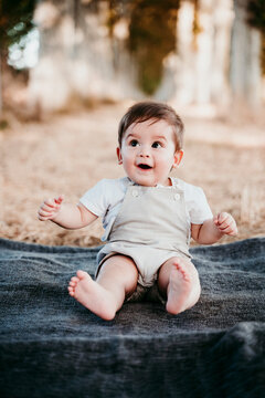 Playful baby sitting on blanket outdoor