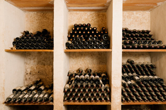Stack of old wine bottles in rack at cellar