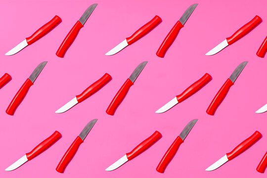 Table knives arranged on pink background