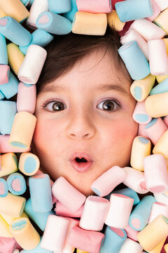 Girl face surrounded with marshmallow looking surprised