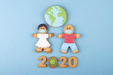 Gingerbread boy and girl in medical masks, gingerbread coronavirus and planet earth