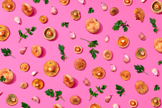 Assorted mushrooms, parsley and garlic on pink background