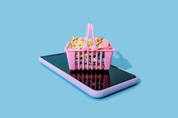 Miniature shopping basket lying on top of smart phone