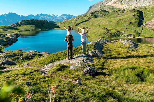 Mother and father carrying daughters on shoulders looking at view while standing during sunny day