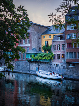 Belgium, Namur Province, Namur, Motorboat moored along city canal stretching in front of row of townhouses