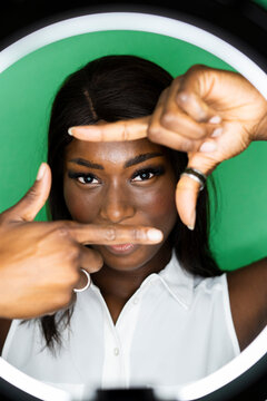 Young woman making finger frame against green background