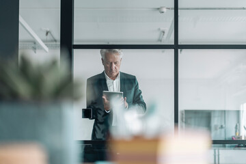 Businessman using digital tablet while standing at office