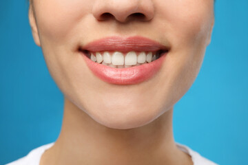 Obraz premium Woman with healthy teeth and beautiful smile on blue background, closeup. Cosmetic dentistry