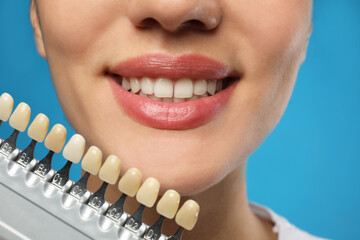 Woman checking her teeth color on blue background, closeup. Cosmetic dentistry