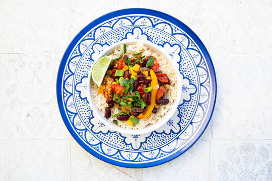 Bowl of Mexican rice with tomatoes, bell pepper, tofu, kidney beans, corn, scallion and lime