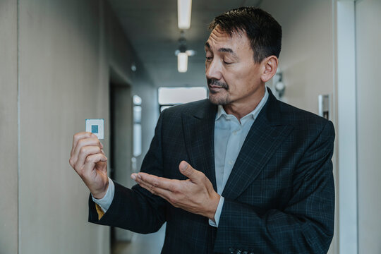 Business man showing computer chip while standing at clinic corridor