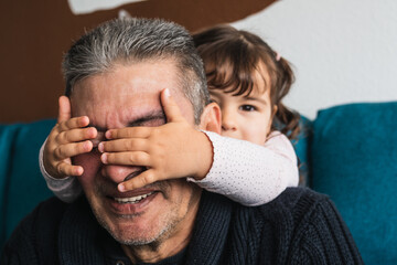 Granddaughter covers her eyes to her grandfather to surprise him.