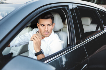 Fototapeta na wymiar Handsome man with smartphone in modern car