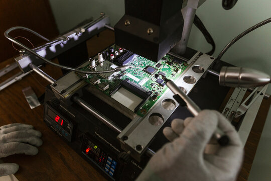 Electronics expert examining damaged circuit board at repair shop