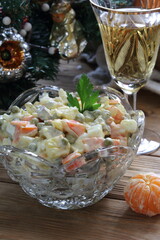 Fototapeta na wymiar Traditional Russian Christmas Salad Olivier with champagne and tangerines