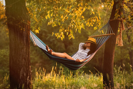 Young woman resting in comfortable hammock at green garden