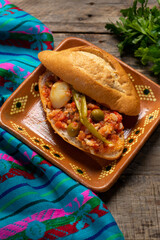Mexican style cod sandwich called torta a la vizcaina on wooden background
