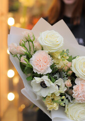 Flower shop. Beautiful bouquet of mixed flowers in light bright color in woman's hands. Work of the florist at a flower shop.  Fresh cut flower.