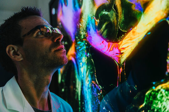 Male scientist examining projection of human brain with nerve fiber while standing at laboratory