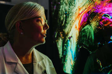 Female scientist examining projection of human brain with nerve fiber while standing at laboratory