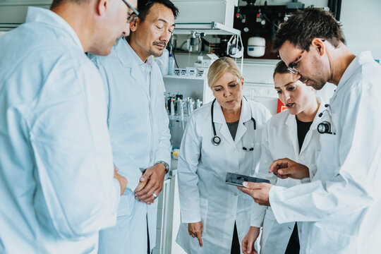 Scientist team working together on digital tablet while standing at laboratory