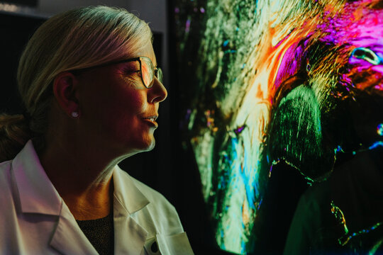 Female scientist examining projection of human brain with nerve fiber while standing at laboratory
