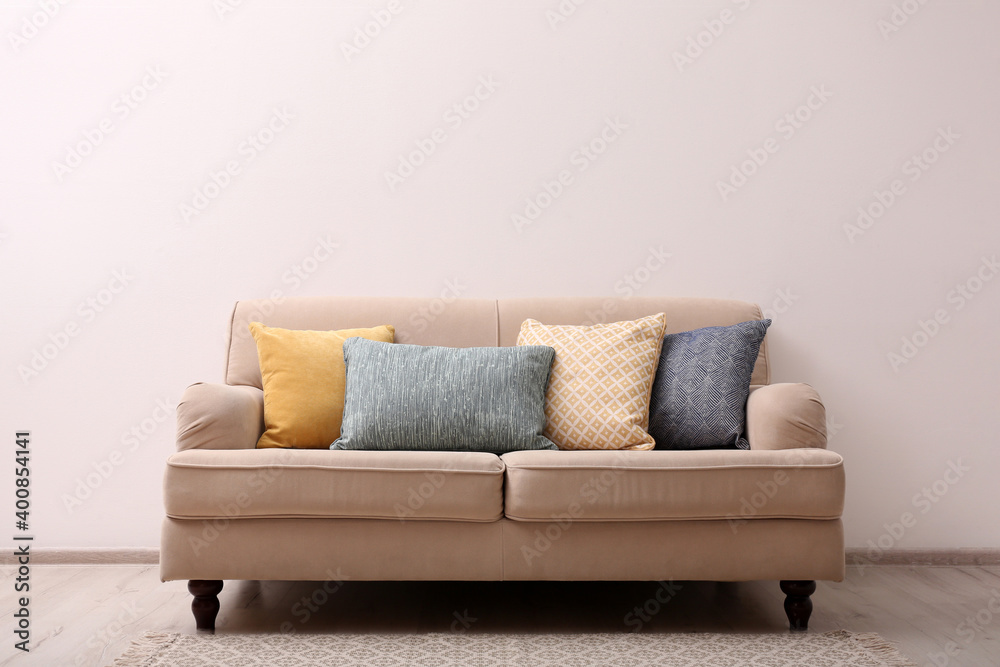 Poster Comfortable beige sofa near light wall indoors, space for text. Simple interior