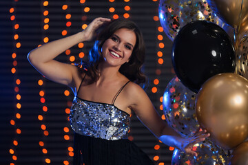 Happy woman with air balloons against blurred festive lights. Christmas party