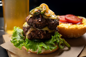 Cheese burger with caramelized onion and jalapeno pepper on dark background