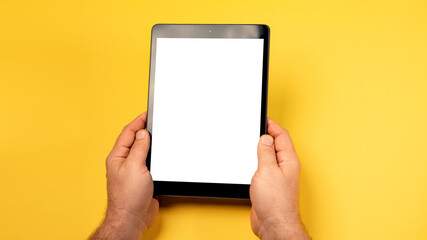 Cropped close up view mock up image man hand hold black tablet pc white blank screen isolated yellow bright background. Digital modern gadget, remote distance work concept. Free empty space for text
