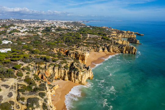 Portugal, Faro District, Albufeira, Drone view of Praia da Mare das Porcas, Praia da Coelha and surrounding cliffs with city in background