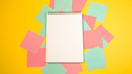 Top view colorful memo sticky pin clips empty notes scattered chaotic manner. Paper blank notepad with pen isolated yellow background. Business, education, working concept. 