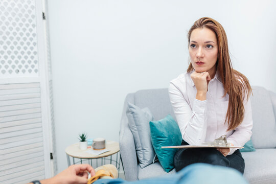 Doctor with hand on chin listening to man problems while sitting at office