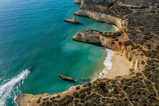 Drone view of tourboat sailing by Praia do Pontal and Praia da Morena beaches