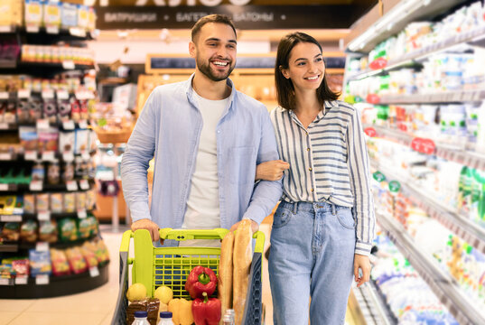 Young cheerful couple with the cart shopping in supermarket