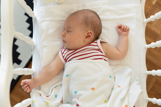 High angle view of baby girl lying down in crib at home