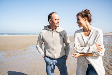 Smiling daughter and father talking while walking at beach