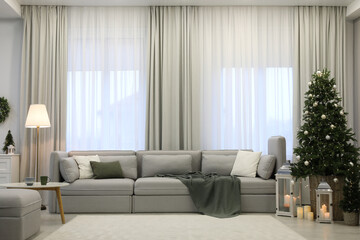 Elegant living room interior with comfortable sofa and Christmas decor