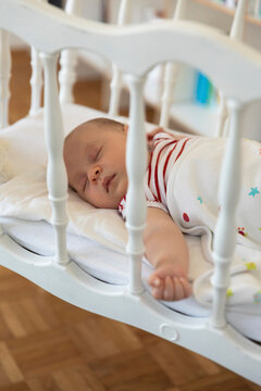Baby girl lying down in crib at home