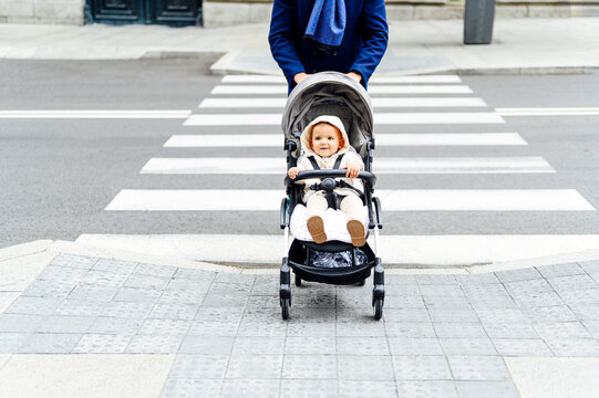 Man crossing road with baby boy sitting in baby stroller at city