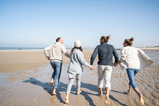 Family holding hands while running on beach