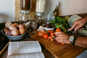 Cropped image of human hand cutting tomato in kitchen at home
