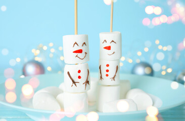 Funny snowmen made of marshmallows in plate, closeup. Bokeh effect