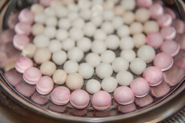 Top side view of red and white tangyuan (tang yuan, glutinous rice dumpling balls) in steel bowl for Winter solstice festival food.
