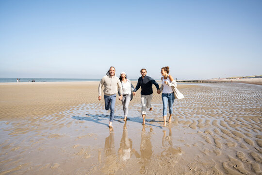 Happy family holding hands while running on beach