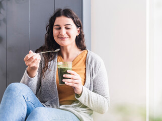 Woman smiling while drinking smoothie at home